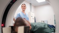 Eine medizinische Technologin für Radiologie begleitet einen Patienten bei der MRT-Untersuchung.