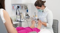 Eine Podologin behandelt die Füße einer Patientin.