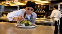 Eine gastronomische Assistentin garniert eine Speise, bevor diese die Küche verlässt.
