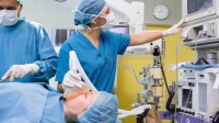 Eine Patientin in einem Krankenhaushemd wird während der Operation von einer anästhesietechnischen Assistentin betreut.