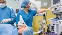 Eine anästhesietechnische Assistentin überwacht die Vitalfunktionen einer Patientin während der Operation.