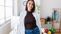 Eine Diätassistentin steht an ihrem Schreibtisch, auf dem sie gesunde Lebensmittel für die Patientengespräche vorbereitet hat.