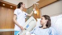Eine Gesundheits- und Krankenpflegerin überprüft die Einstellung des Tropfes einer Patientin. 