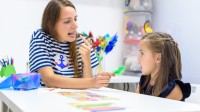 Eine Logopädin übt mit einem Vorschulkind die korrekte Aussprache von Silben.