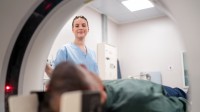 Eine medizinische Technologin für Radiologie betreut einen Patienten, der im MRT-Gerät liegt.