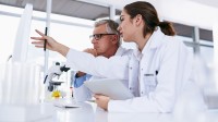 Eine medizinische Technologin für Veterinärmedizin und ein Fachtierarzt für klinische Laboratoriumsdiagnostik analysieren gemeinsam die Ergebnisse einer Blutuntersuchung am Computer.