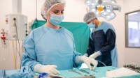 Eine operationstechnische Assistentin in OP-Kleidung richtet Instrumente auf einem Tisch für eine bevorstehende Operation her.