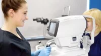 Eine Orthoptistin führt einen Sehtest mit einem medizinischen Gerät bei einem Kind durch.