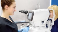 Eine Orthoptistin führt einen Sehtest mit einem medizinischen Gerät bei einem Kind durch.