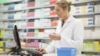 Eine pharmazeutisch-technische Assistentin recherchiert den Warenbestand eines Hautpflegeprodukts.