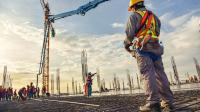 Ein Beton- und Stahlbetonbauer kontrolliert eine gießende Betonpumpe auf der Baustelle.