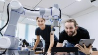 Eine technische Assistentin erprobt gemeinsam mit einem Techniker den Prototyp eines neuen Roboters.
