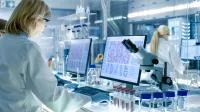 Eine Biologielaborantin mikroskopiert verschiedene Proben Blutzellen und wertet die Bilder am Computer aus.