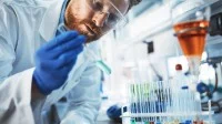 Ein chemisch-technischer Assistent untersucht im Labor eine Probe mit verschiedenen chemischen Reagenzien.