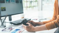 Ein Fotodesigner gleicht die erstellten Bilder auf seiner Kamera mit denen am Computer ab.