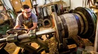 Ein Böttcher arbeitet an einer Ausdrehmaschine in einer Fassfabrik in München.