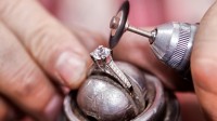 Nahaufnahme von einem Diamantring, der mit einer Polierscheibe, die auf einem Dremel steckt, poliert wird.
