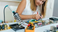 Eine elektrotechnische Assistentin baut auf einer Leiterplatte eine neue Versuchsanordnung auf.
