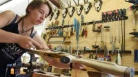 Eine Büchsenmacherin arbeitet in ihrer Werkstatt an einem Nußholzschaft für einen Kunden.