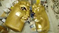 Bühnenplastiker arbeiten an einer riesigen Maske, die aus Kunststoff geschnitzt, mit Fiberglas überzogen und mit Blattgold vergoldet wurde.