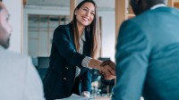 Eine Fremdsprachenkorrespondentin begrüßt zwei ausländische Geschäftspartner.