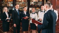 Ein Assistent für Hotelmanagement macht ein Teambriefing, bevor das Bankett beginnt.