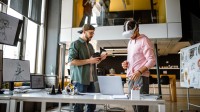 Zwei Assistenten für Medieninformatik testen im Großraumbüro ein AV-Produkt. 
