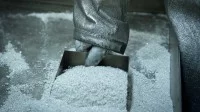 Ein Mitarbeiter eines Metallwerkes nimmt eine Probe von dem Silberpulver.