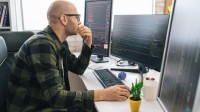 Ein mathematisch-technischer Assistent entwickelt in seinem Büro ein Softwareprogramm am Computer.