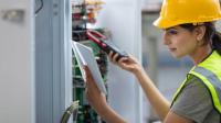 Eine Elektronikerin für Gebäudesystemintegration überprüft Leiterplatten.