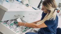 Eine medizinische Dokumentationsassistentin sucht aus einem Hängeregister eine Krankenakte heraus. 