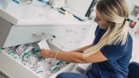 Eine medizinische Dokumentationsassistentin sucht eine Krankenakte aus dem Schrank heraus.