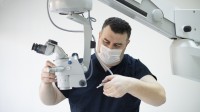 Ein technischer Assistent für medizinische Gerätetechnik wartet ein medizinisches Mikroskop.