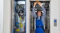 Ein Elektroniker für Informations- und Systemtechnik repariert einen defekten Fahrstuhl.