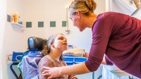 Eine Pflegeassistentin wäscht ein Mädchen, welches in einer Wohngemeinschaft für pflegebedürftige Menschen lebt.