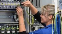 Eine Elektronikerin für Maschinen und Antriebstechnik arbeitet an einer Steuerungseinheit in einem Werk für Kombinationstechnik in Chemnitz.
