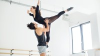 Eine Bühnentänzerin und ein Bühnentänzer proben ein Ballettstück ein.