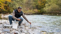 Ein umweltschutztechnischer Assistent untersucht die Wasserqualität eines Fließgewässers.