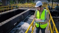 Eine Fachkraft für Abwassertechnik prüft die Qualität des Wassers aus dem Abwasserbehandlungsteich.