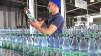 Eine Fachkraft für Lebensmitteltechnik prüft eine Mineralwasserflasche an einer Abfüllanlage in Bad Liebenwerda.