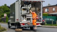 Eine Fachkraft für Rohr-, Kanal- und Industrieservice bereitet hinter einem TV-Kanalinspektionswagen die nächste Kamerafahrt für die Videoüberprüfung der Kanalisation vor. 