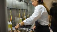 Eine Fachfrau für Systemgastronomie kocht ein deftiges Fleischgericht in einer Pfanne.
