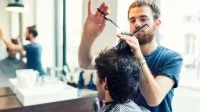 Ein Friseur schneidet im Salon einem Kunden die Haare.