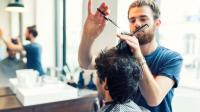 Ein Friseur schneidet im Salon einem Kunden die Haare.