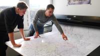 Zwei Geomatiker vom Landesbetrieb Straßenbau Nordrhein-Westfalen überprüfen eine Landkarte, die sie erstellt haben.