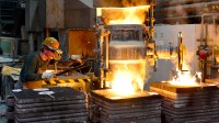 Ein Gießereimechaniker gießt hoch erhitztes Metall in eine Form für ein Werkstück.