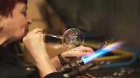 Eine Glasbläserin formt Christbaumschmuck aus erhitztem Glas.