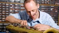 Ein Holzblasinstrumentenmacher arbeitet an einem Baritonsaxophon.