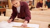 Eine Holzmechanikerin plant die Bearbeitung eines Werkstücks.