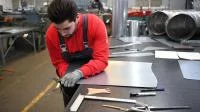 Ein Industrie-Isolierer schneidet einen Blechbogen für eine Isolierung zu.